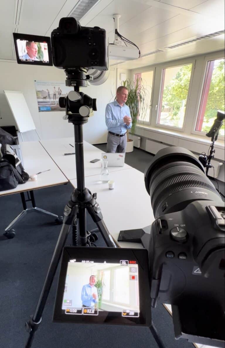 Stativkamera filmt Mann vor Fenster im Büro, Monitor zeigt Aufnahme – Videoproduktion Winterthur