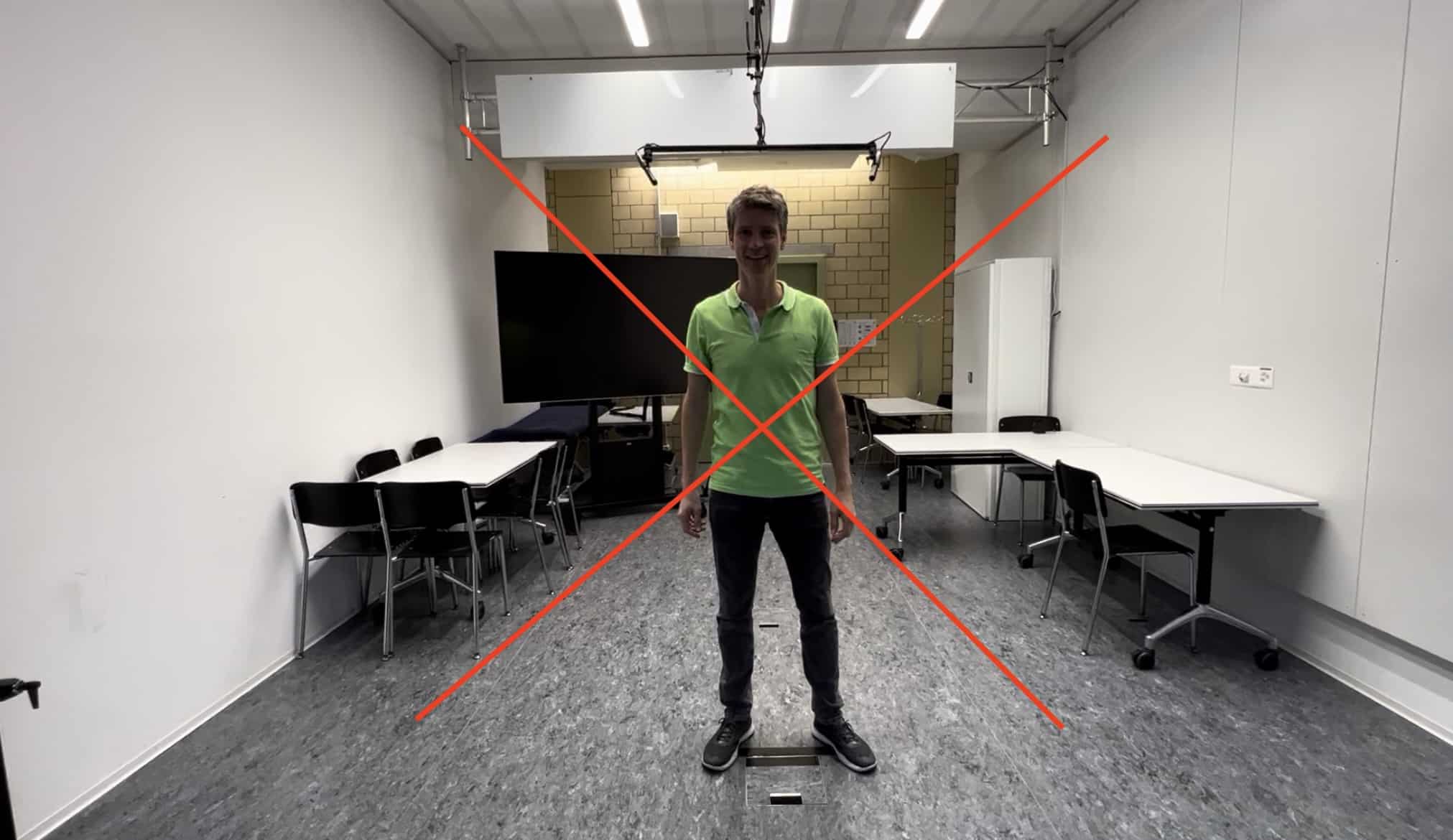 Mann in grünem Polo in Studio mit Monitor, Tischen und Studiobeleuchtung – Videograf Winterthur