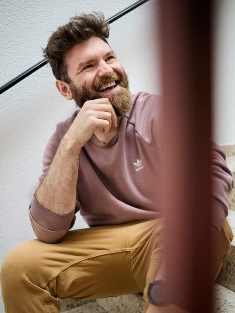 Lächelnder bärtiger Mann auf Treppe, lässiges Outfit; Fotograf Winterthur, Fotostudio