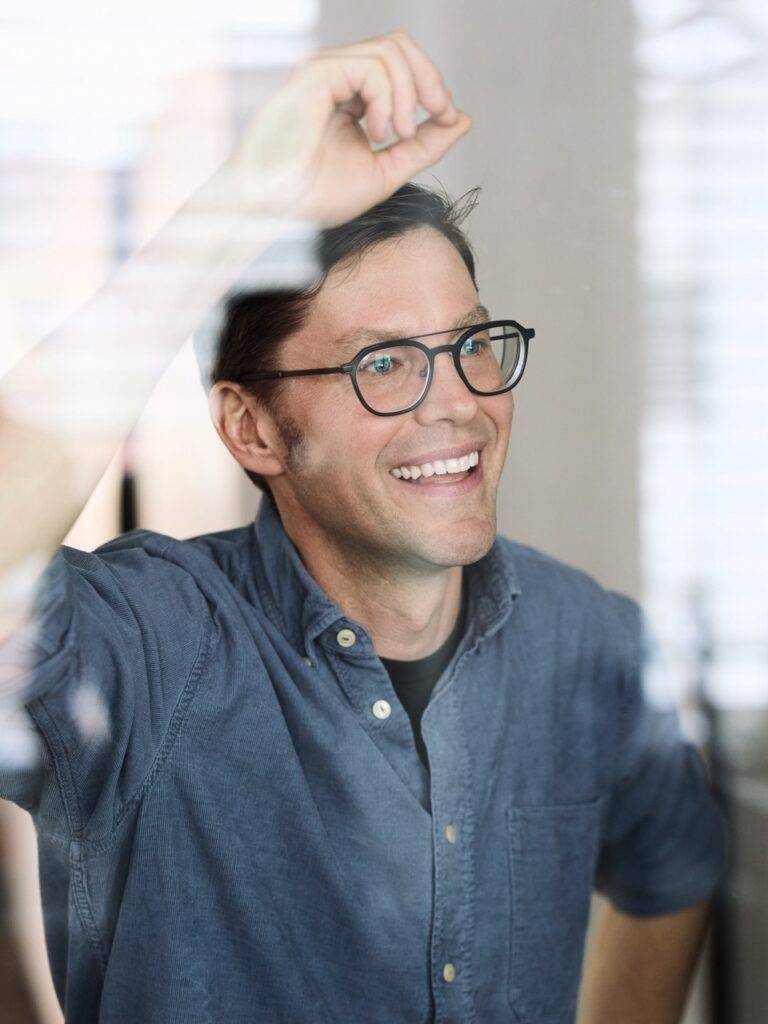 Lächelnder Mann mit Brille vor Fensterreflexion, Business-Porträt – Fotograf Winterthur