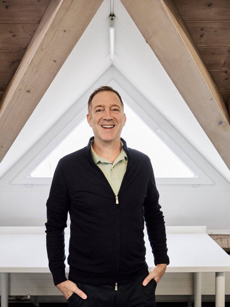 Lächelnder Mann vor dreieckigem Dachfenster im hellen Fotostudio – Fotograf Winterthur